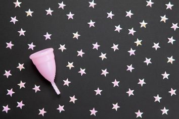 Pink menstrual cup against black background with stars